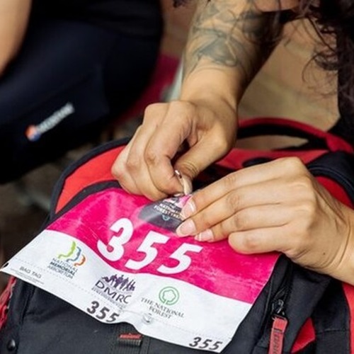 Participant pinning their number to their backpack before participating in the charity trek