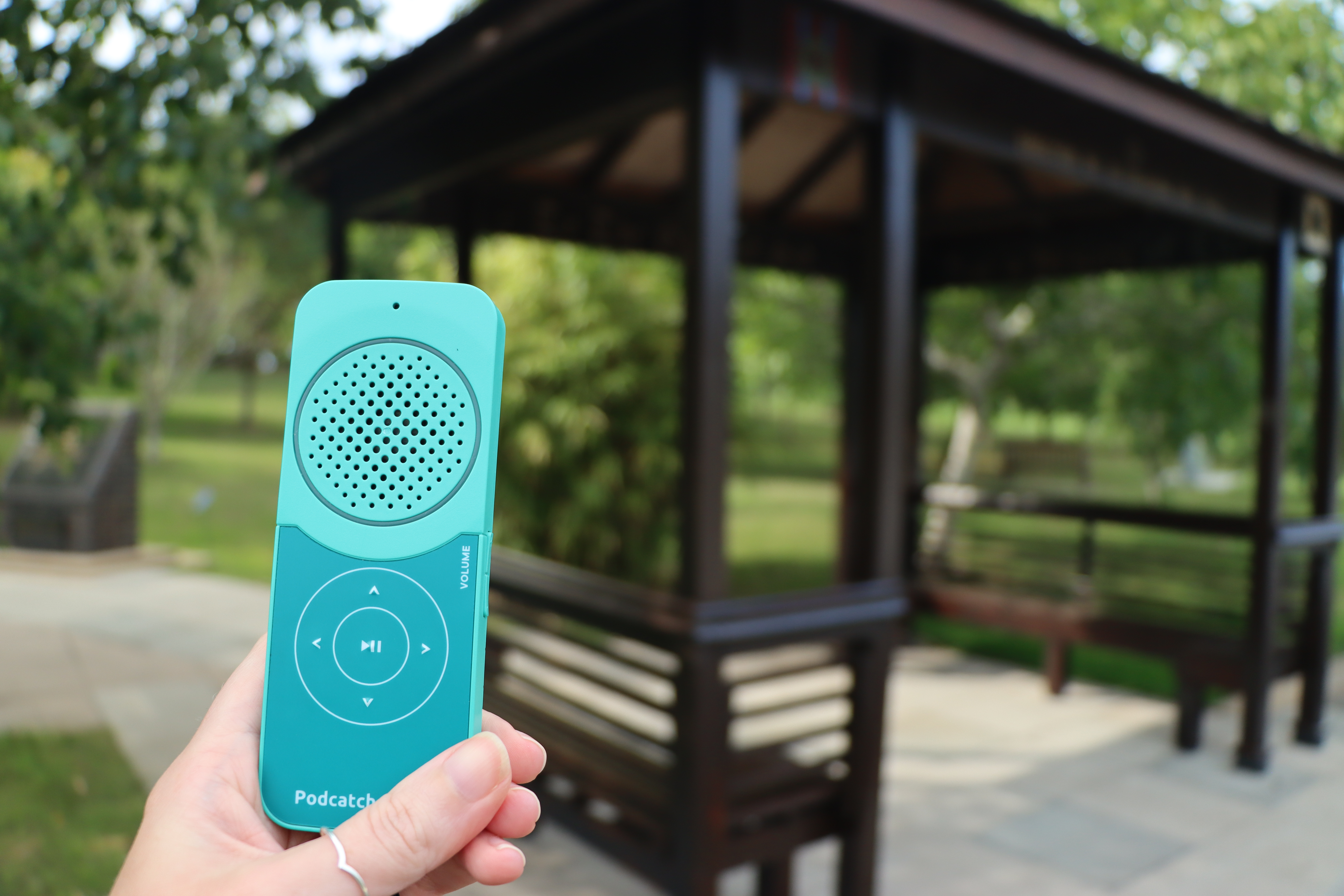 a person holding up a podcatcher audio device next to the Changi Lych Gate, one of the locations of the poems in the Poetic Reflections trail