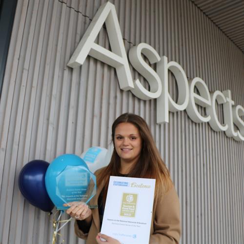 Aspects Team Member holding the Gold Award and Balloons