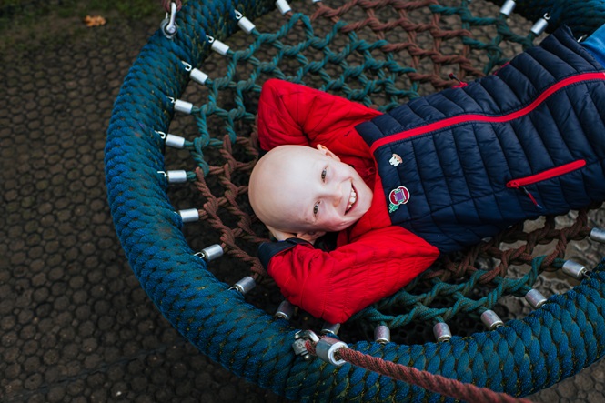 A young boy plays on a swing the Children's Sensory Play Garden