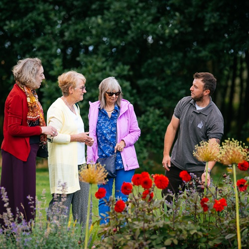 A group of three people talking to a gardener