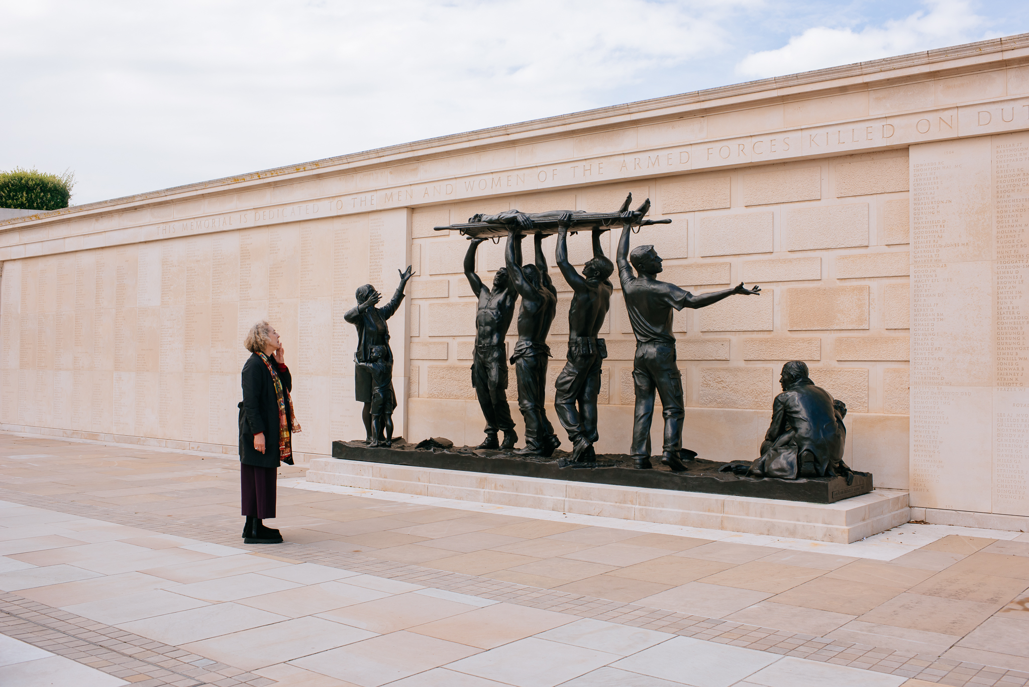 A person on the Armed Forces Memorial looking at sculptures by Ian Rank Broadley